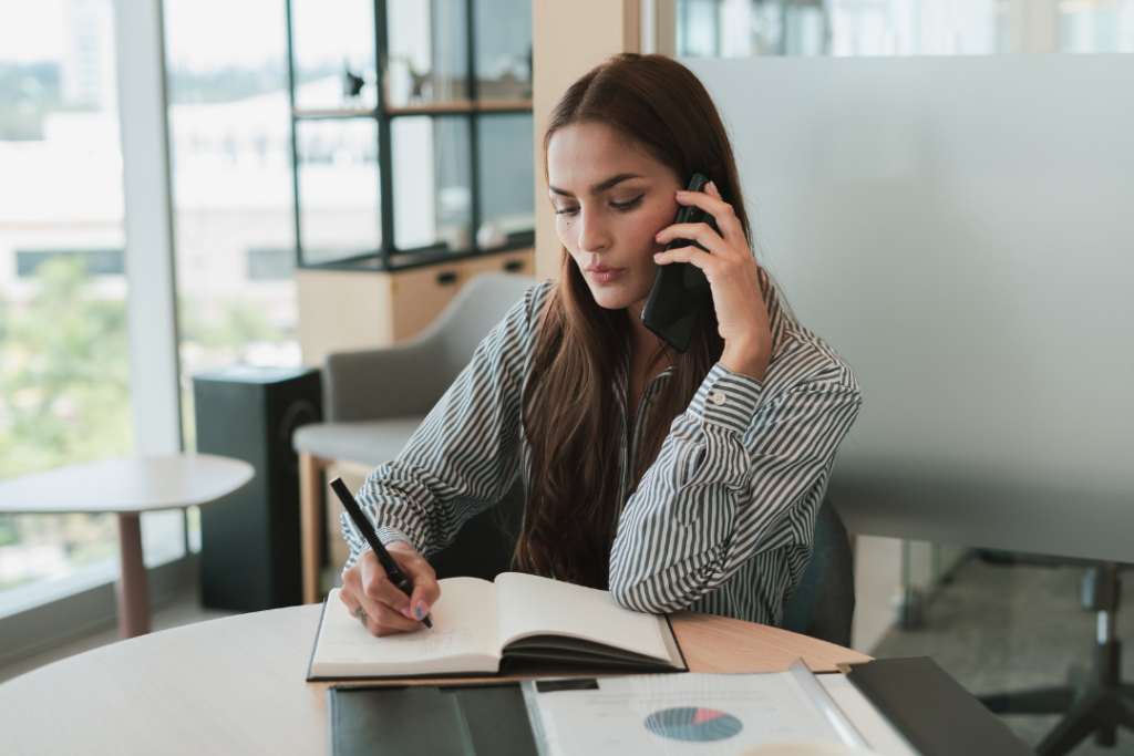 Maman qui prend des notes sur son carnet pendant son appel avec la Motivologue