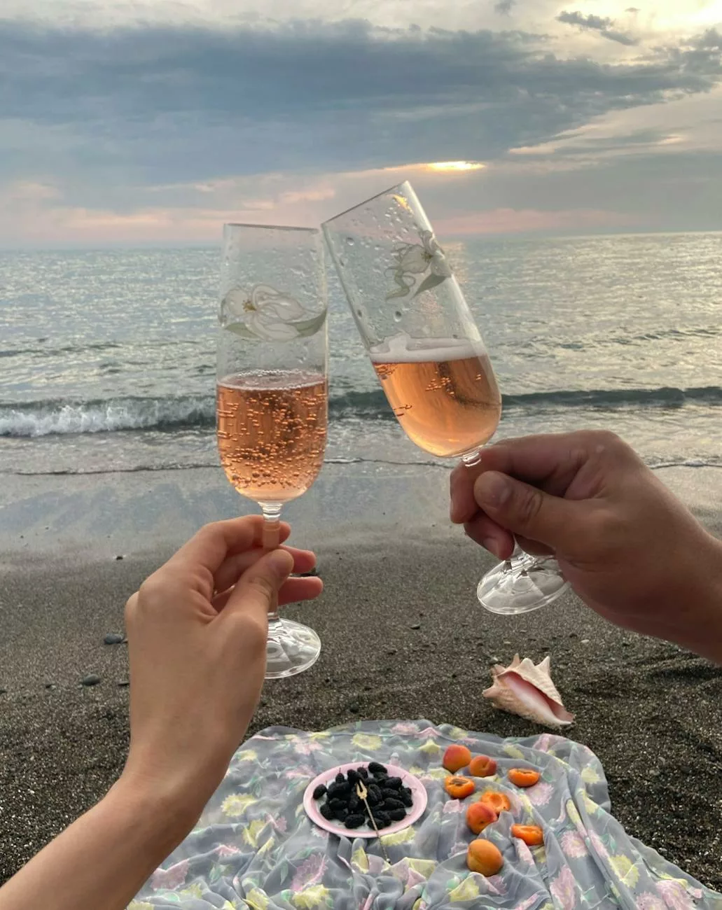 couple clinking glasses of champagne on seashore