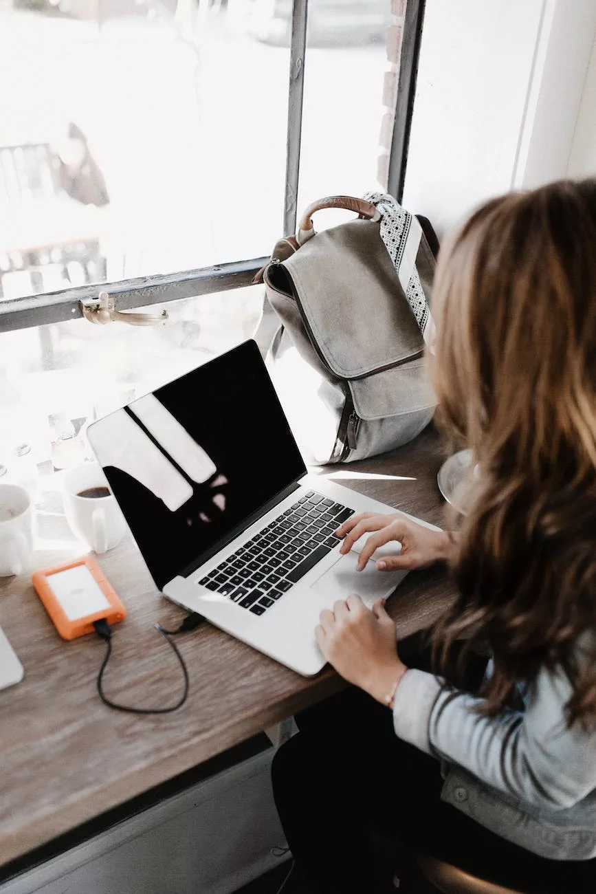 close up photography of woman sitting beside table while using macbook