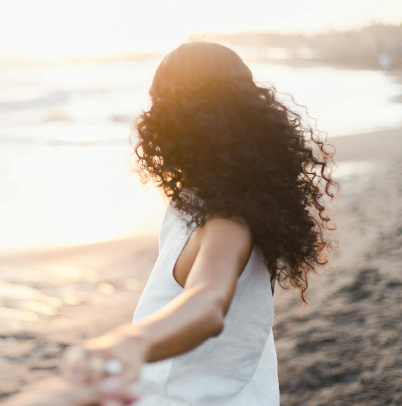 unrecognizable woman holding hand of partner while contemplating ocean